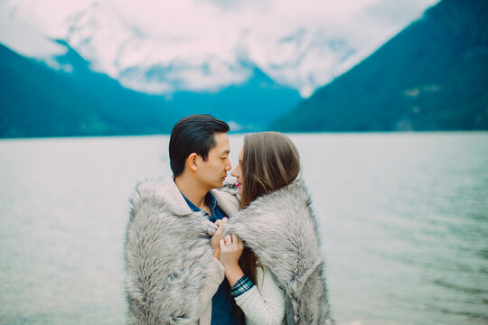 Young couple holding each other in front of lake with blanket