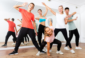 Fototapeta na wymiar Group portrait of jolly teenagers with young female choreographer in modern dance studio