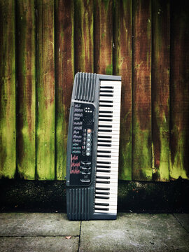 A keyboard propped up against a fence