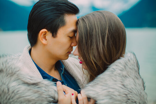 Young couple holding each other in front of lake with blanket