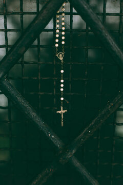 Close up of crucifix on rosary hanging from church's grate