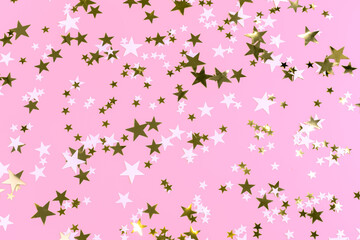 festive beautiful gentle pink background with shiny gold and white stars. concept of beauty and children's parties