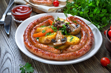 Tasty homemade grilled sausages with baked herb potatoes, mushrooms, cherry tomatoes and ketchup on a wooden background. Oktoberfest snack. Summer picnic dish