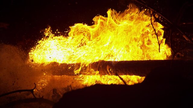 SLOW MOTION, CLOSE UP: Cinematic shot of orange flames burn through dry branches and twigs in the pitch black of a quiet summer night. Blazing fire engulfs a heap of dry firewood near quiet campsite.