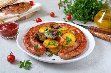 Tasty homemade grilled sausages with baked herb potatoes, mushrooms, cherry tomatoes and ketchup on a wooden background. Oktoberfest snack. Summer picnic dish
