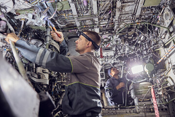 Engineers working with aircraft in repair hangar