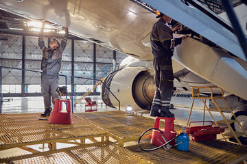 Engineer working on aircraft wing in aircraft maintenance factory