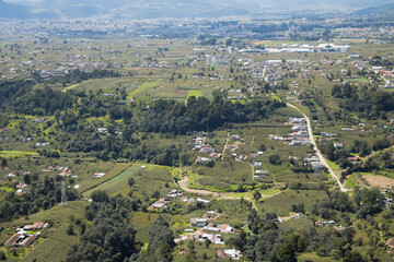 Obraz premium Rural villages surrounded by trees and crops seen from above - Aerial view of a part of a rural suburb in Quetzaltenango Guatemala