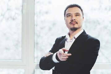 Asian successful businessman standing near panoramic window. Business suit.