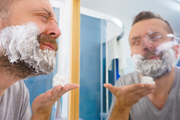 Guy shaving his beard in bathroom