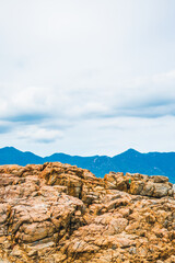 Beautiful natural composition, vivid orange brown yellow stone rock shabby cliff cracks, cumulus cloud sky, mountain background. Vacation after pandemic, beauty nature power. Vertical stories format