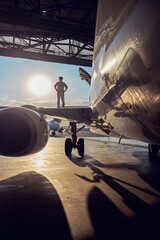 Image of aircraft with captain in the aviation hangar - obrazy, fototapety, plakaty