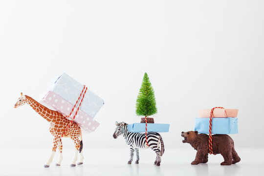 Toy animals carrying Christmas gifts on white.