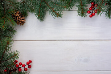 Fototapeta na wymiar Christmas tree branches with pinecone and red berries on white wooden background and copy space for your text. Flat lay