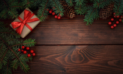 Fototapeta na wymiar Christmas tree, gift, pinecones, red berries on a wooden brown background.Copy space for your text. Flat lay
