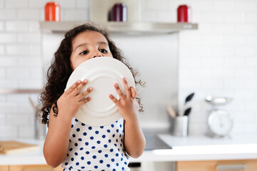 Cute little girl licks last remaining drops from plate