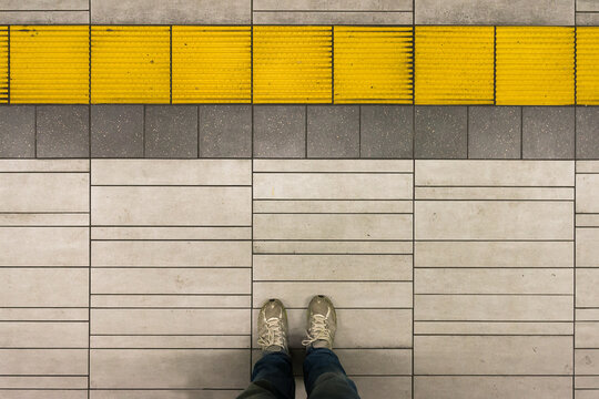 Standing on subway platform with yellow stripe