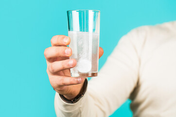 White pill and a glass of water in man hands. Health concept. Close up of man holding a pill. Glass of water tablet. Glass with efervescent tablet in water with bubbles