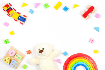 Baby kids toy frame on white background with teddy bear and colorful wooden toys. Top view, flat lay