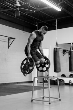 Fit and muscular african american athlete jumping while holding heavy weights