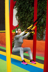 A young woman squatting with athletic straps