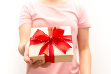 Close up shot of female hands holding a small gift wrapped with red ribbon. Girl in pink t-short, white background. Selective focus.