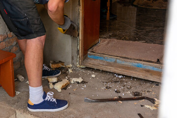 Dismantling of old entrance doors, old wooden box and door, the master cuts, cuts a wooden box from the wall with a hand saw.