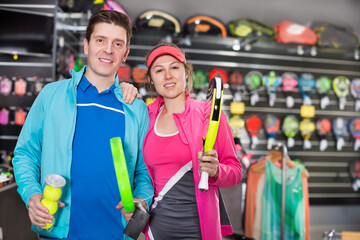Woman and man are choosing padel racket in the sportive store. Focus on both persons