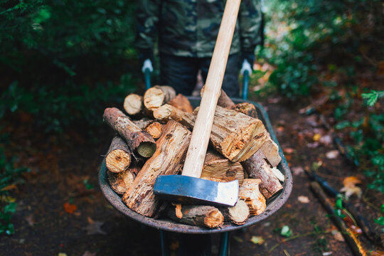 A wheelbarrow full of chopped wood adn a ax