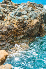 Beautiful natural composition landmark background. Bright vivid brown gray stone rock shabby cliff cracks texture mountains, lazur sea water splash. Concept of geology, tourism cruise, power in nature