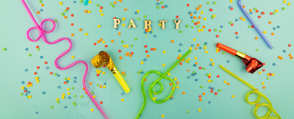 Bright festive party background - cocktail straws and party whistles on blue background with scattered sugar sprinkles.