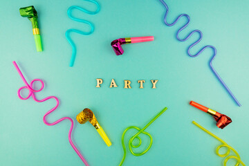 Bright festive party background - cocktail straws and party whistles on blue background.
