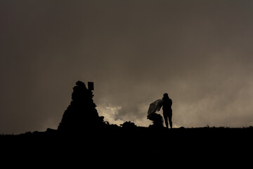 Couple of tourists in the clouds on top of Mount Brebeneskul, tourists standing on top in the raincoats, gloomy weather.