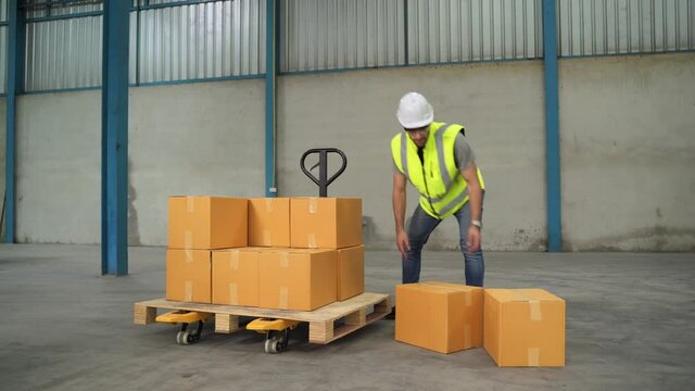 The engineer lifts the boxes to a cart and drags them in a warehouse.
