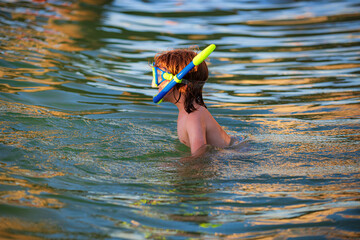 Boy playing on the beach on summer holidays. Happy child swimming in the sea. Kid snorkeling in the...