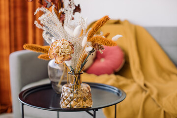 Flowers in vase on table at stylish home interior. Fall colors, copy space.
