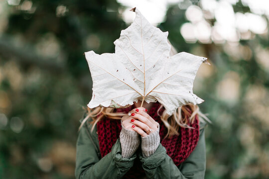 Woman holding a large leaf in front of her face
