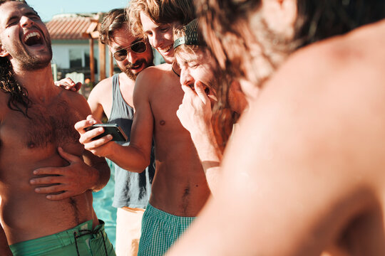 a group of friends laugh at a photo on a phone