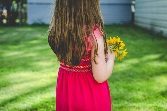 Back of child holding small bouquet of flowers