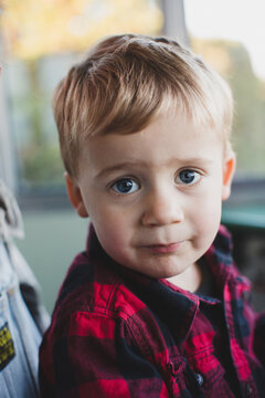 Cute toddler boy in plaid shirt with big eyes looking at camera