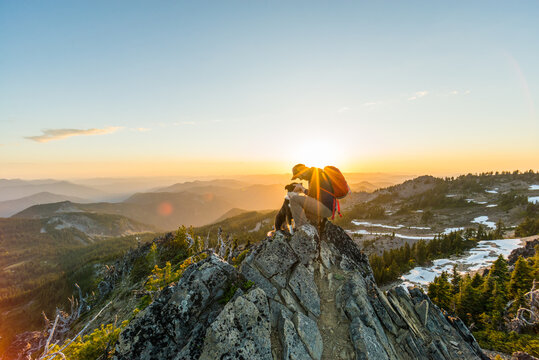 Man and his dog ontop of mountain at sunset