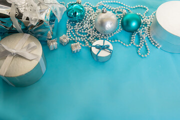 Christmas gifts wrapped with white and blue ribbons, balls, and decorations on a blue background with copy space