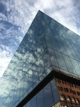 Low angle view of modern office building and sky, clouds reflecting in windows