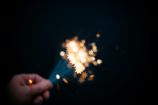 Intentionally blurred hand golding blurry sparklers creating star shapes