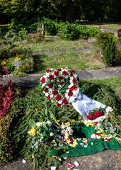 Blumenkranz mit Schleife auf einem Urnengrab
