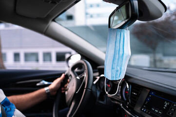 Protective face mask hanging from a car's rear view mirro