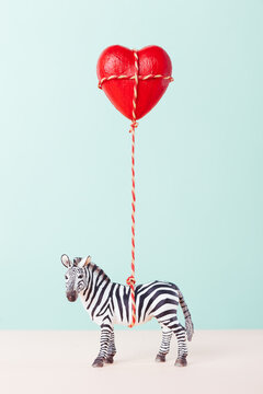 Zebra toy holding a red heart balloon.