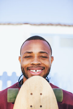Portrait of a man with his longboard outside.