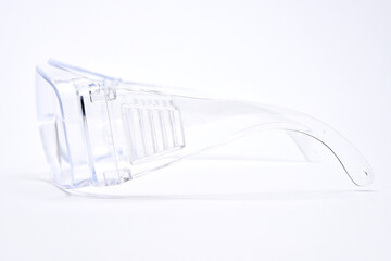 Protective transparent plastic glasses, side view on white background