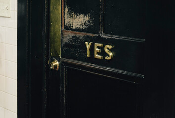 Black & gold yes worn wooden restaurant door. Close-up